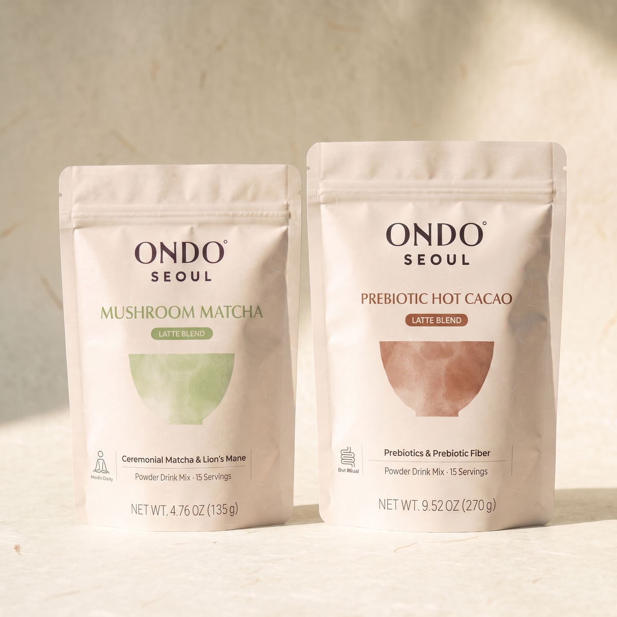 Day & Night Duo: two pouches, Focus Mushroom Matcha Latte Blend and Prebiotic Hot Cacao Latte Blend, on ivory hanji paper.